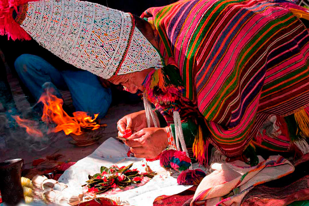 Chamán andino durante una ceremonia de pago a la tierra en el Valle Sagrado, preparando ofrendas sobre una manta tradicional