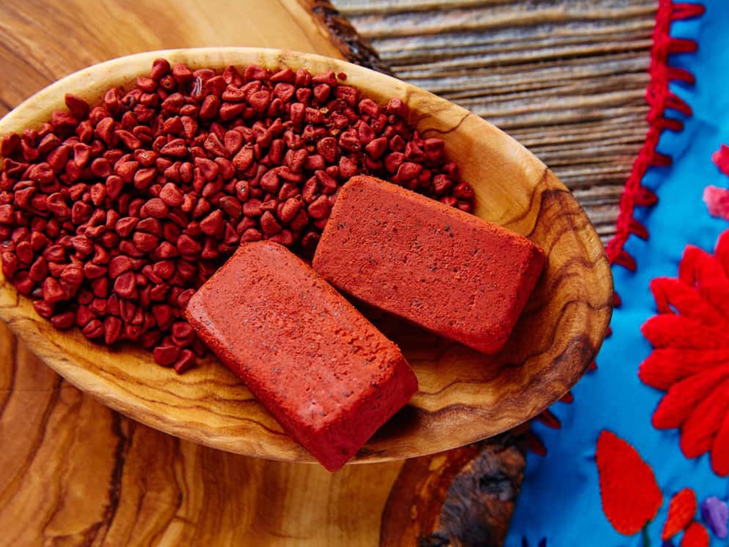emillas y bloques de achiote en recipiente de madera