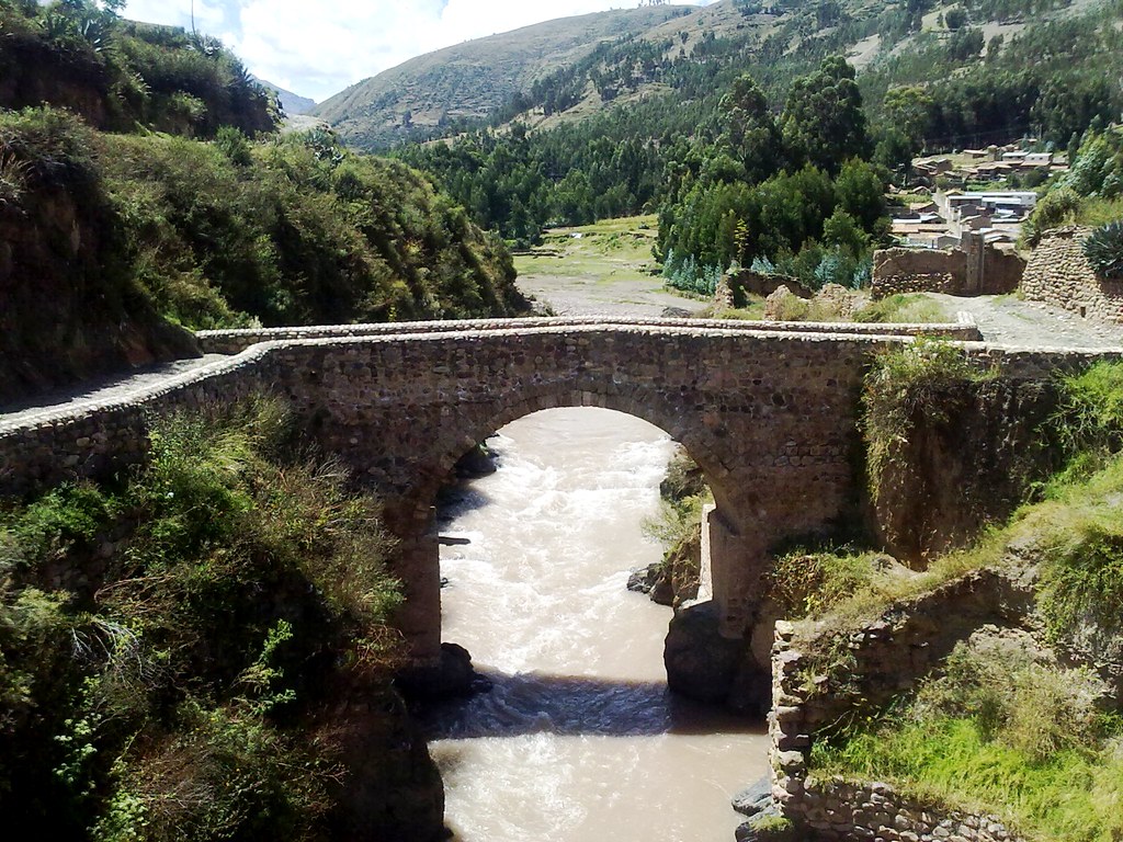 Puente colonial de Checacupe en Cusco, construido en piedra sillar y cal y canto, con arco semicircular sobre el río Pitumarca