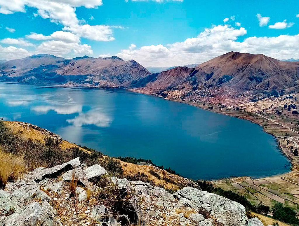 Vista panorámica de la laguna Pomacanchi rodeada de cerros suaves en el altiplano cusqueño