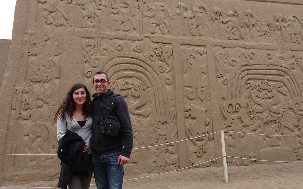 Pareja de visitantes frente a los relieves tallados de la Huaca El Dragón en Trujillo, Perú.