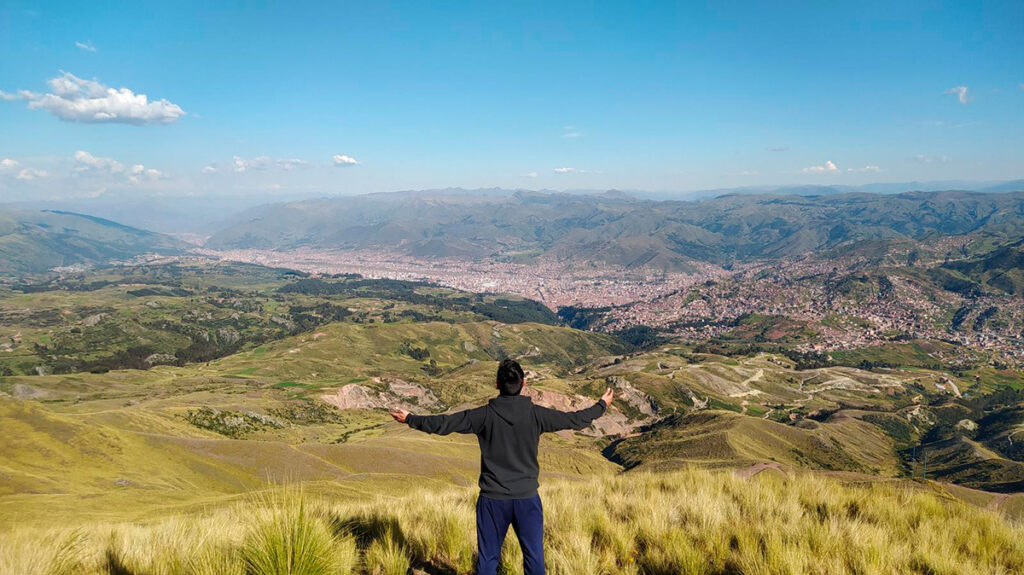 Persona contemplando el valle de Cusco desde el Apu Senqa, cerro tutelar considerado protector espiritual en la cosmovisión andina