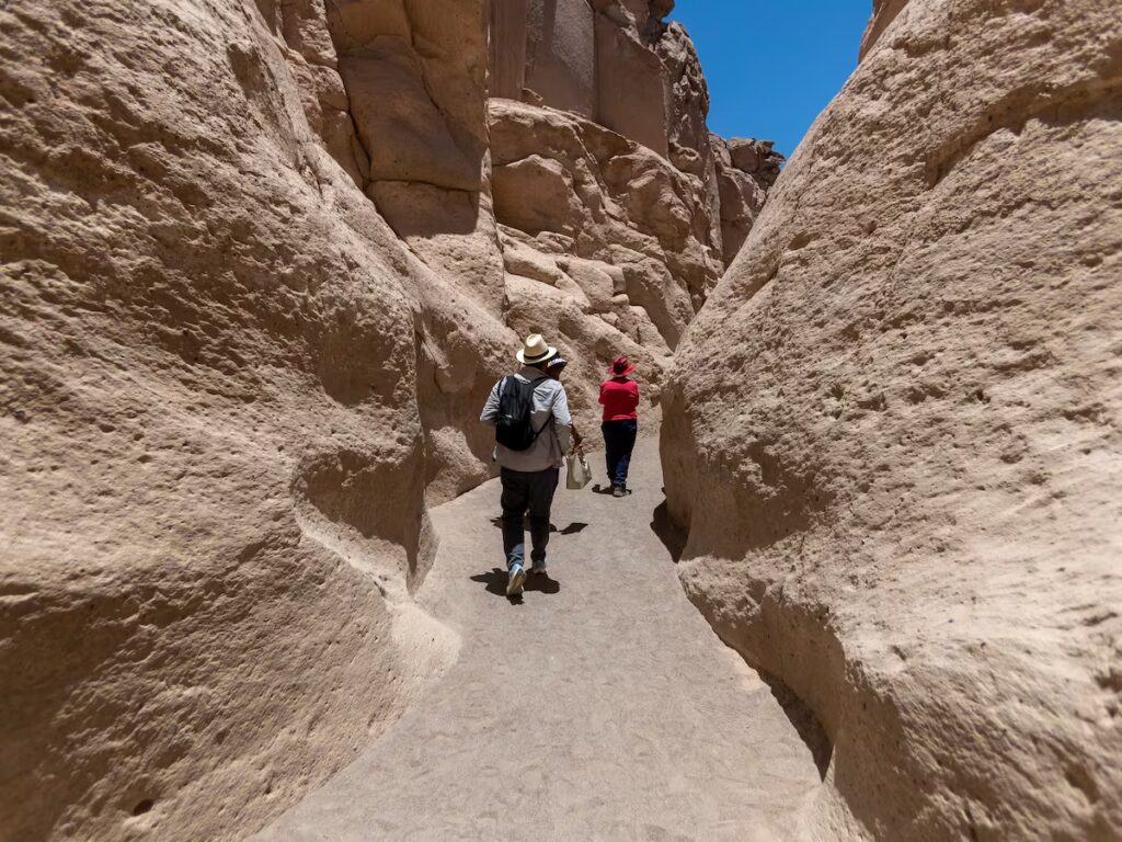 Turistas caminando por la quebrada de Culebrillas en la Ruta del Sillar de Arequipa, rodeados de altos muros de piedra volcánica