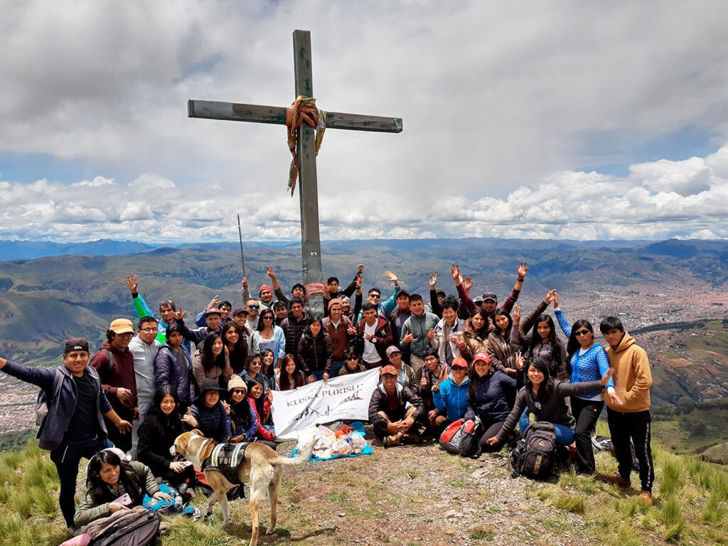 Grupo de peregrinos en el Apu Pikol, Cusco, junto a una cruz ceremonial en la cima de la montaña tutelar