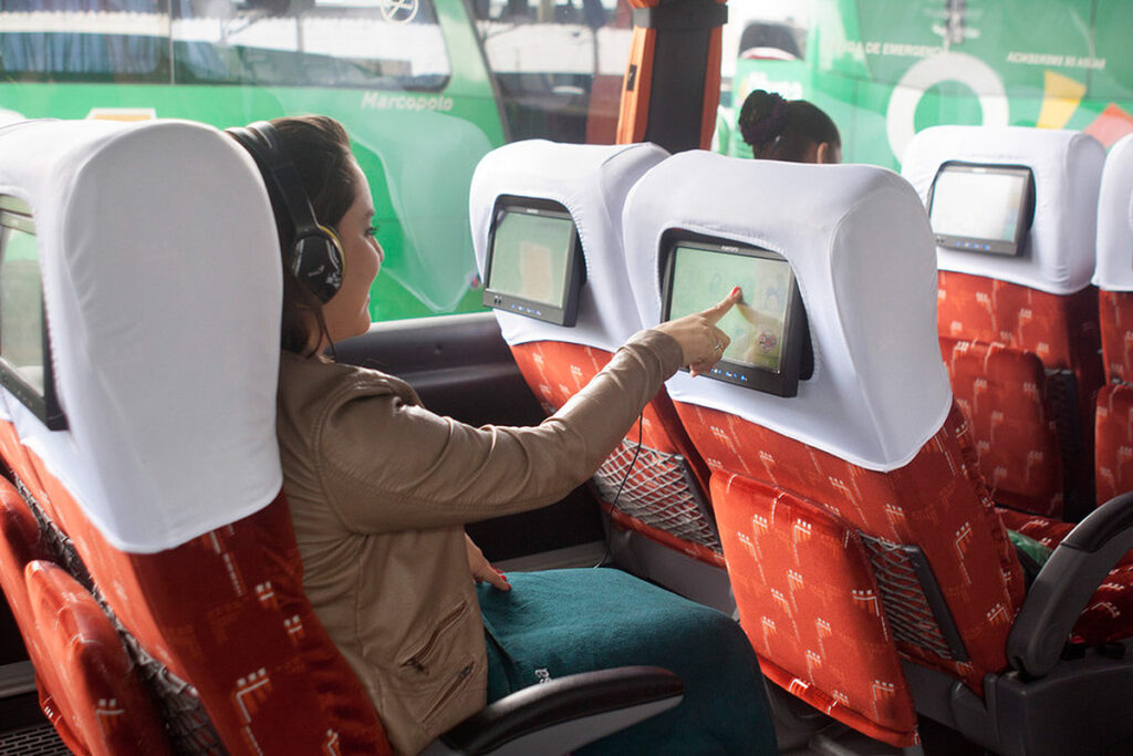 Pasajera en bus interprovincial de larga distancia con asientos reclinables y pantallas individuales