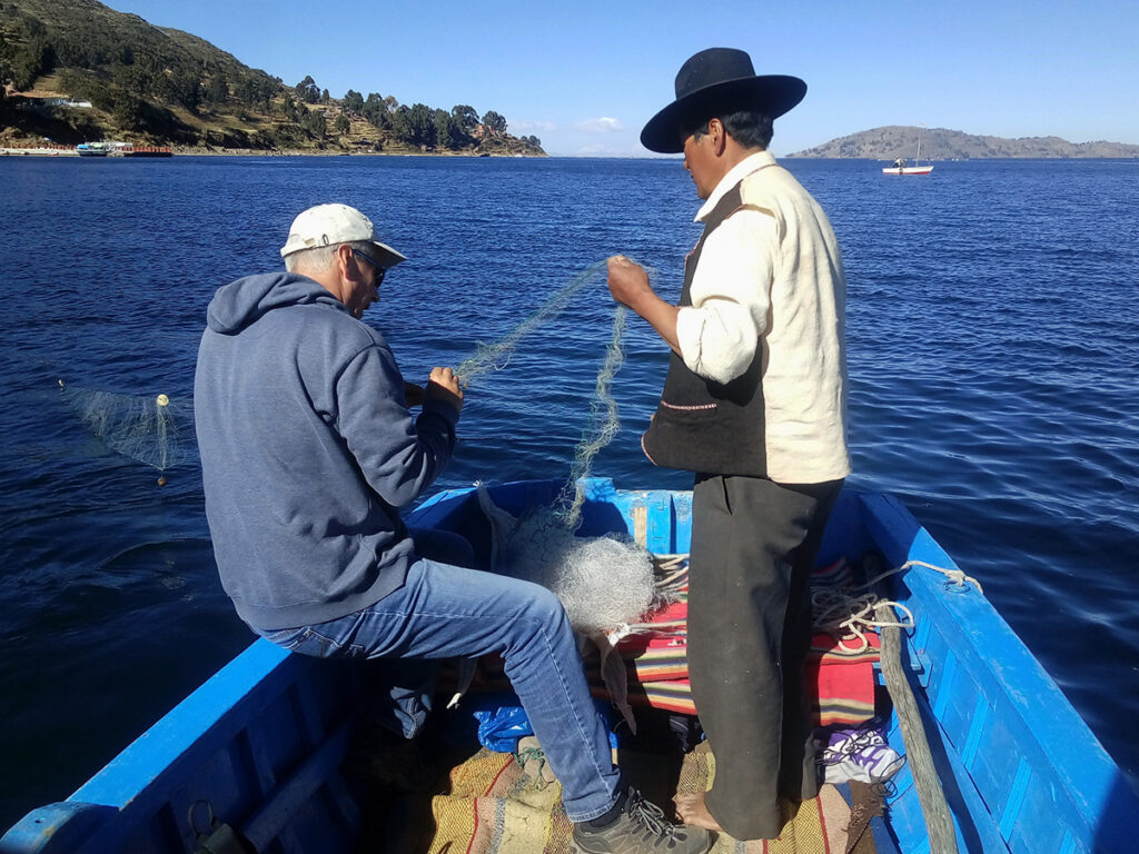 Pescadores artesanales en una embarcación pequeña durante una faena en el Lago Titicaca, Perú