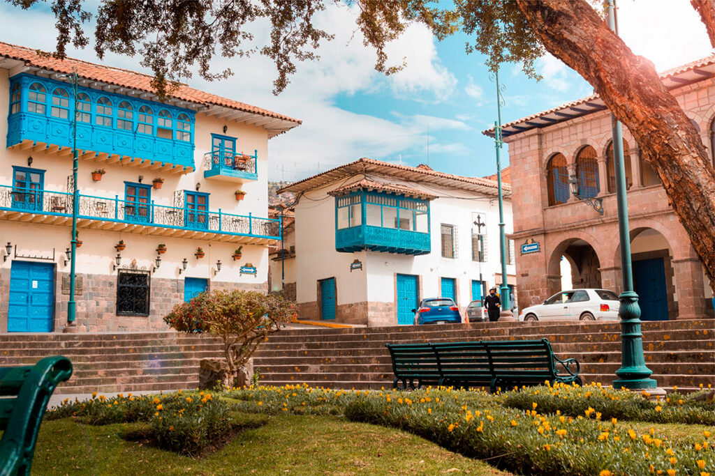 Casonas coloniales con balcones azules en la Plazoleta Regocijo del Cusco, rodeadas de jardines y áreas de descanso