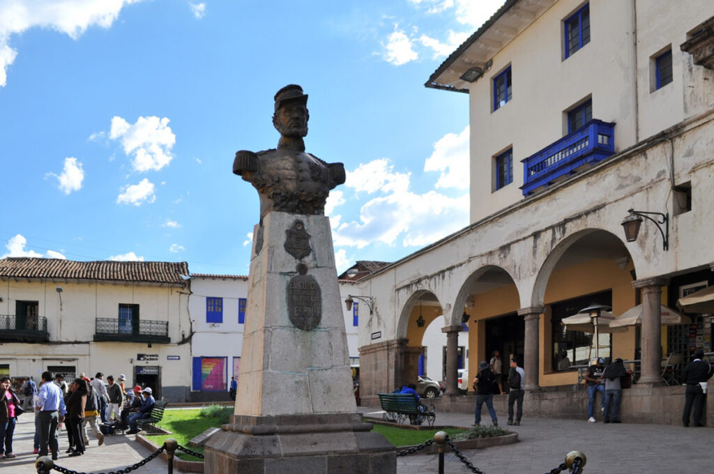 Plazoleta Espinar en Cusco, con busto escultórico central, portales coloniales y ambiente cotidiano