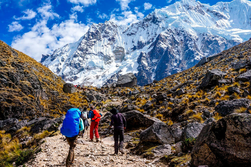 Grupo de excursionistas caminando por la ruta Salkantay con nevados andinos al fondo durante un trekking de altura