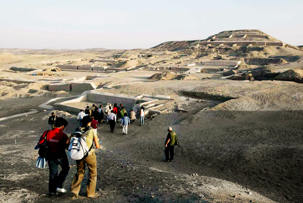 Turistas recorriendo el centro ceremonial de Cahuachi en Nazca, rodeado con la gran pirámide en segundo plano