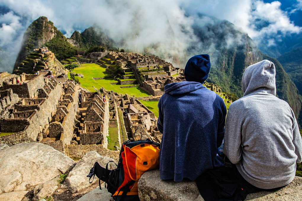 Turistas observando Machu Picchu con neblina en temporada baja en Perú