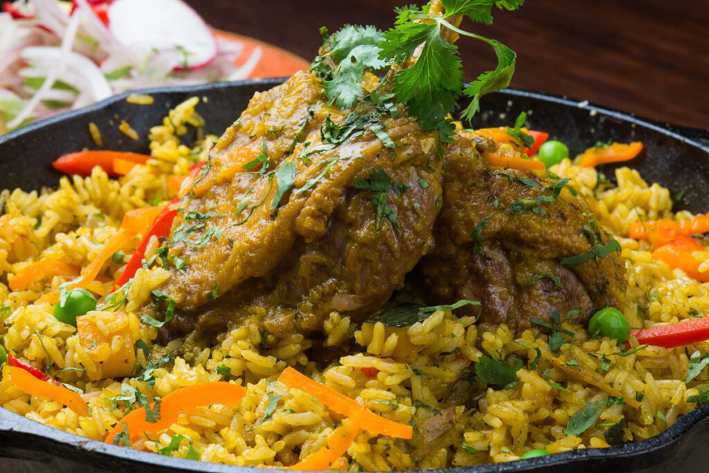 Arroz con pato a la chiclayana servido con zarza criolla, preparado con chicha de jora y culantro, un clásico del valle de Lambayeque que destaca en la cocina norteña