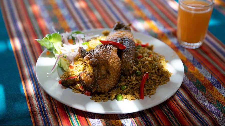 Arroz con pato a la chiclayana servido con zarza criolla y chicha de jora, un clásico de Lambayeque preparado con culantro y hierbas que reflejan la cocina artesanal del norte peruano