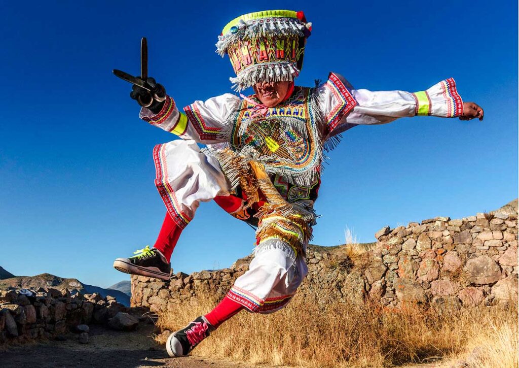 Danzante de tijeras realizando un salto acrobático en los Andes del sur del Perú, con traje bordado y tijeras metálicas que simbolizan el equilibrio entre cuerpo y espíritu