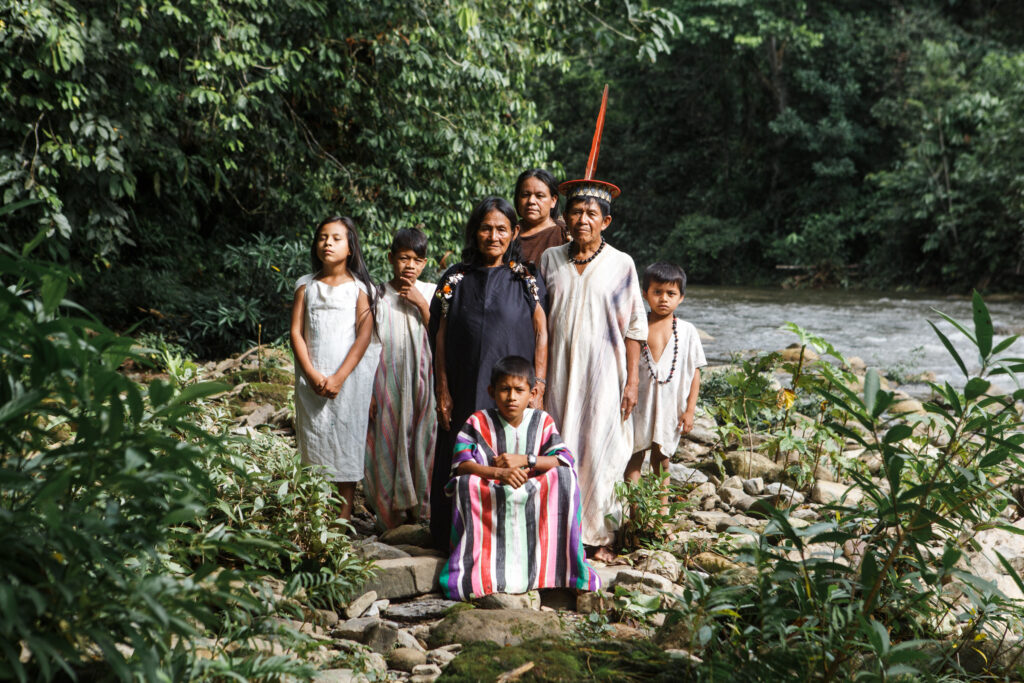 Familia yánesha en la selva central del Perú, junto al río, vestida con atuendos tradicionales que reflejan su vínculo espiritual y cotidiano con la naturaleza amazónica