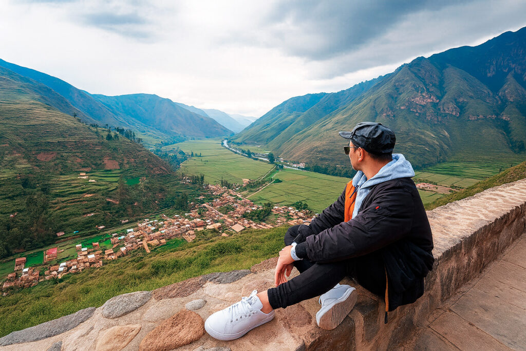 Viajero sentado en el Mirador de Taray observando el Valle Sagrado de los Incas, con el río Vilcanota y las montañas andinas al fondo