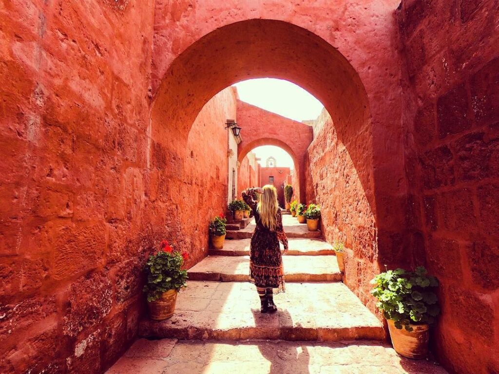 Pasillo interior del Monasterio de Santa Catalina en Arequipa construido en sillar volcánico con muros rojizos y arcos coloniales