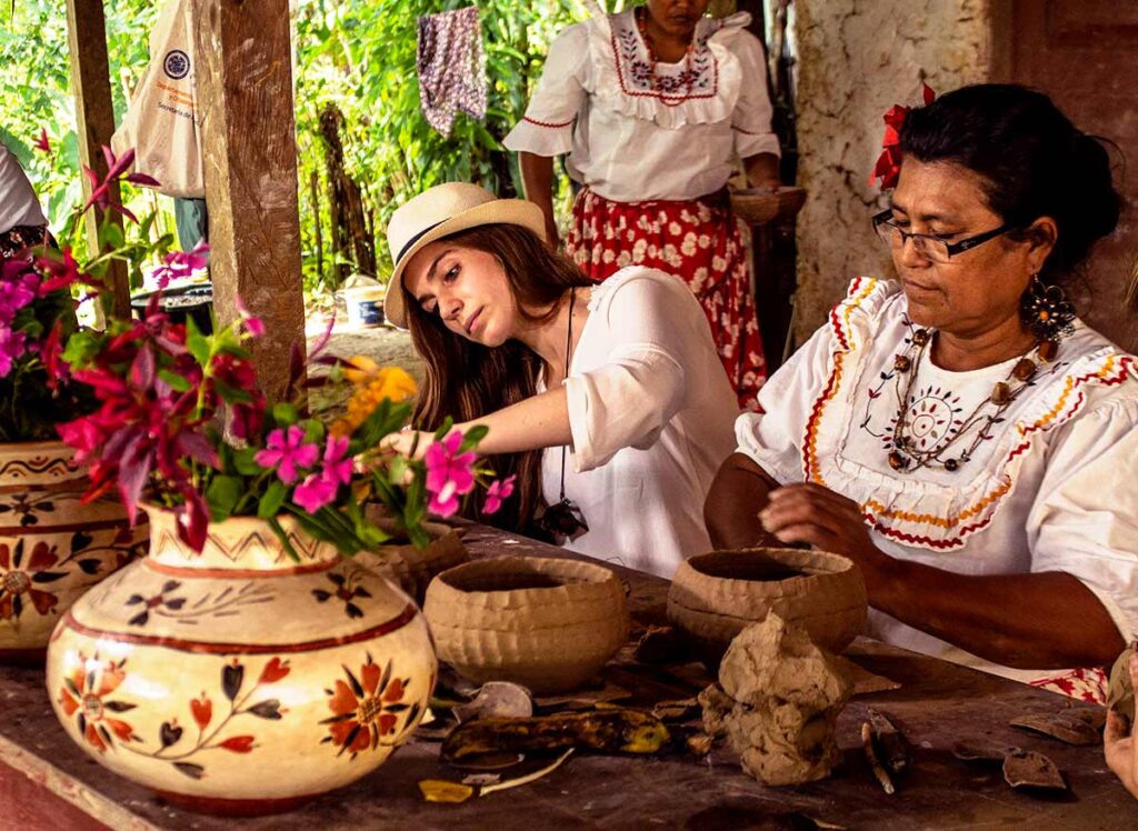 Turista aprendiendo técnicas tradicionales junto a mujeres artesanas kichwa en un taller de cerámica en Chazuta