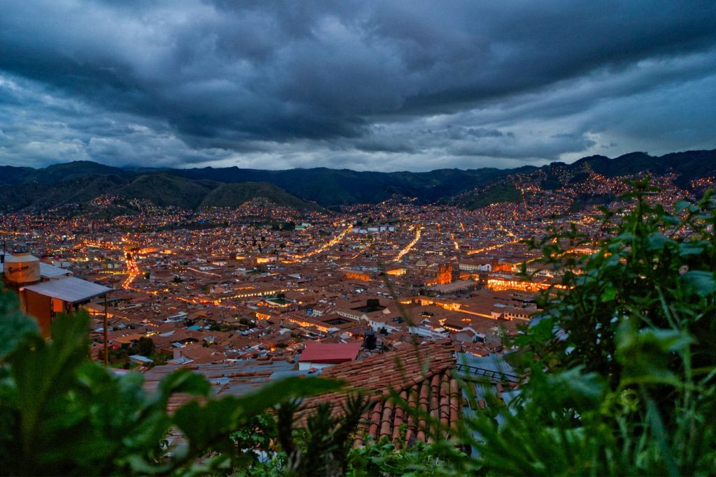 Vista panorámica del centro histórico de Cusco al atardecer durante la temporada de lluvias, con luces encendidas y cielo cubierto
