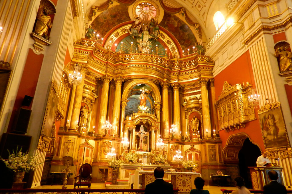 retablo mayor de la iglesia de san pedro en lima, altar barroco limeño dorado con columnas salomónicas y esculturas jesuitas iluminadas
