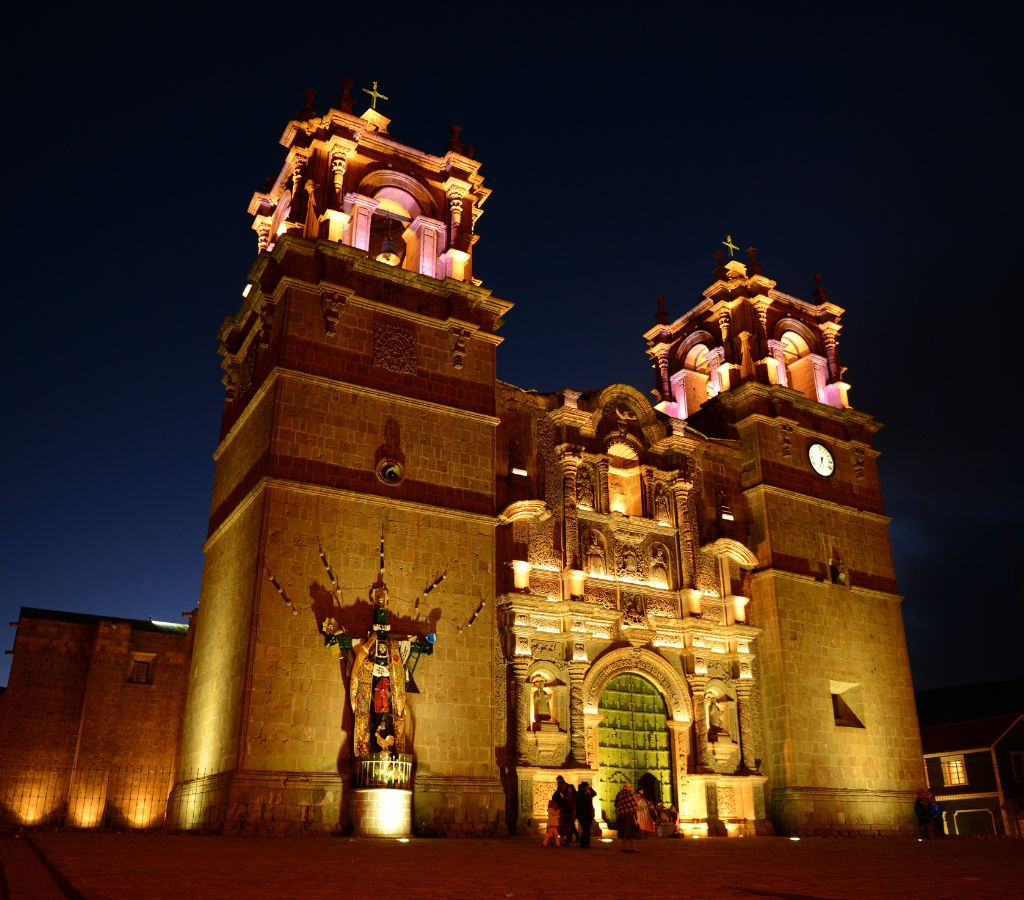 Fachada de la Catedral de Puno iluminada de noche, ejemplo del barroco andino con columnas salomónicas y relieves en piedra tallada