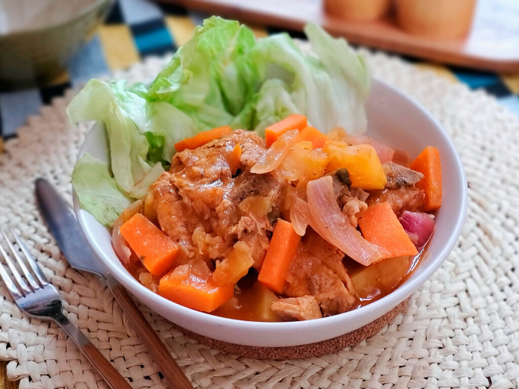 Plato tradicional de Adobo Ayacuchano con carne de cerdo, cebolla y zanahoria, servido en cuenco sobre mantel artesanal