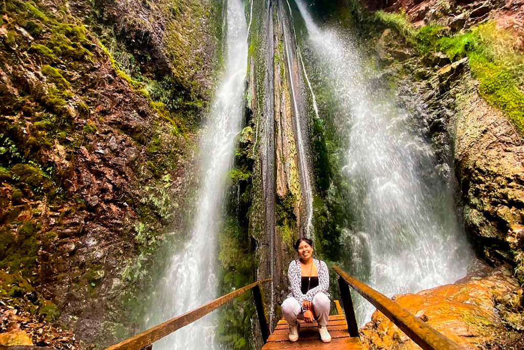 Mujer posando para una fotografía con las carataras de Arín en segundo plano