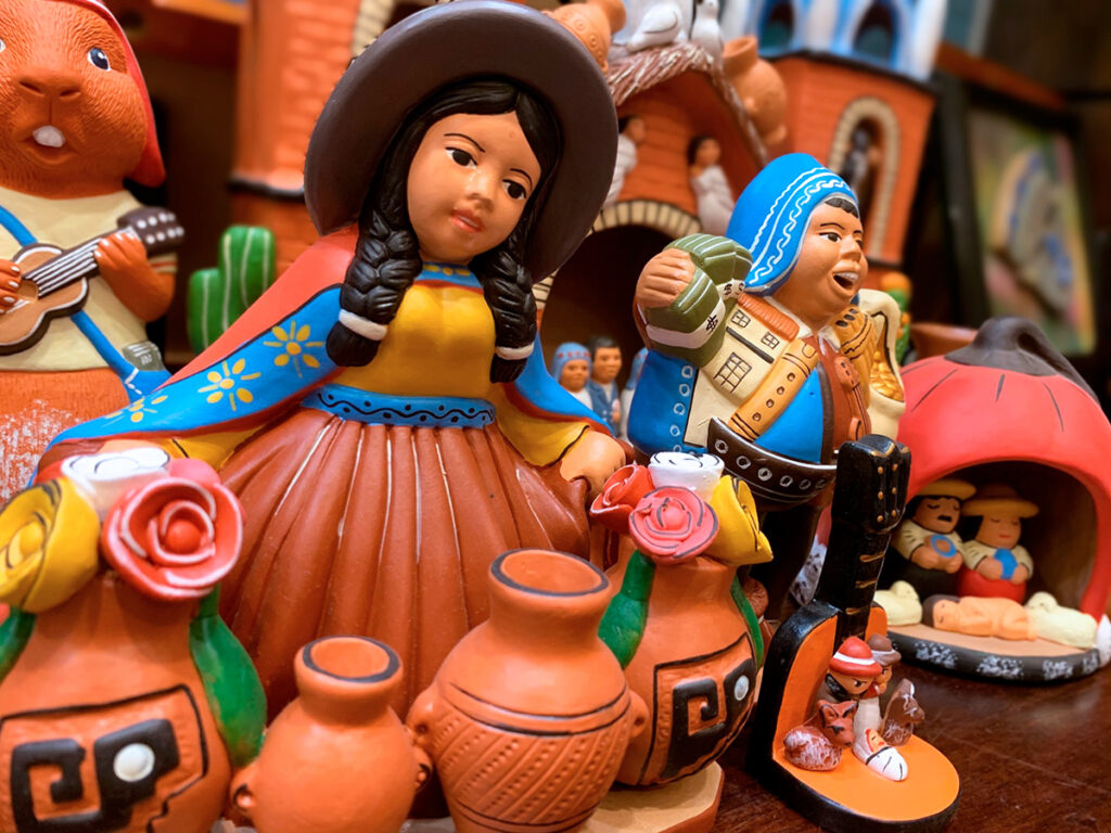 Conjunto de figuras de cerámica de Quinua que representan personajes tradicionales andinos junto a vasijas modeladas y decoradas en tonos terracota y negro
