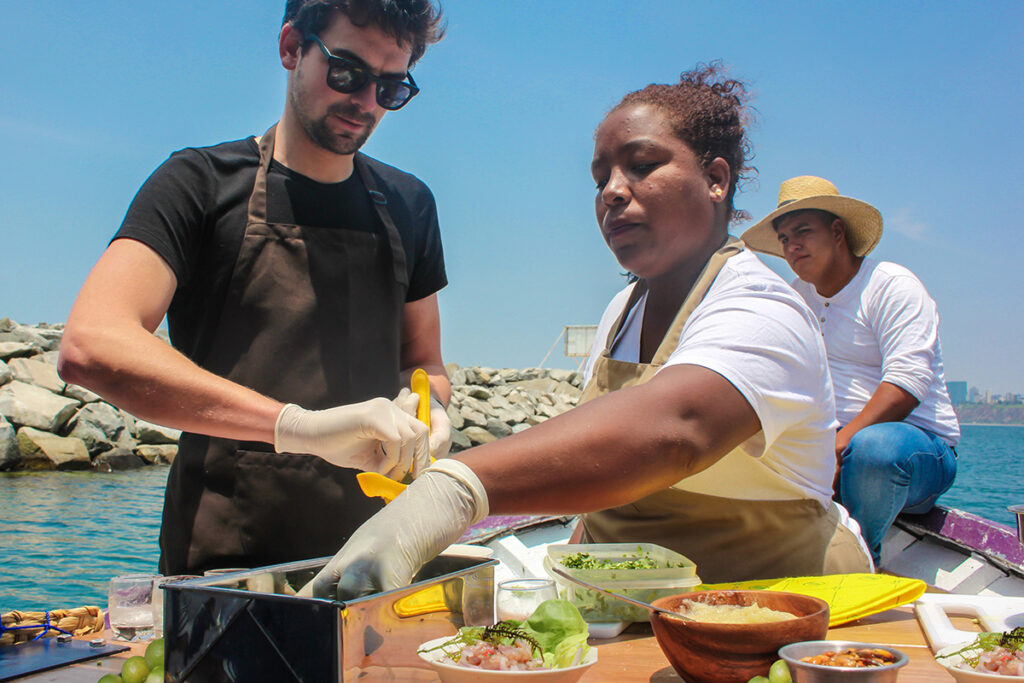 Cocineros preparando platos marinos en la caleta de Chorrillos, con insumos frescos frente al mar