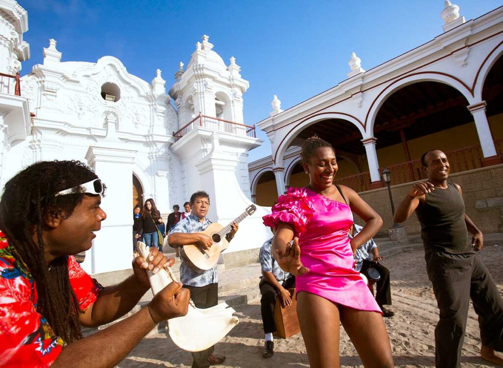 Personas afroperuanas bailando y tocando música tradicional frente a la iglesia de El Carmen, en Chincha, durante una celebración cultural