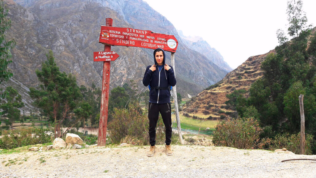 Viajero junto al cartel de ingreso al sendero Lagunas de Huallhua en la ruta hacia Huancaya, dentro de la Reserva Nor Yauyos Cochas