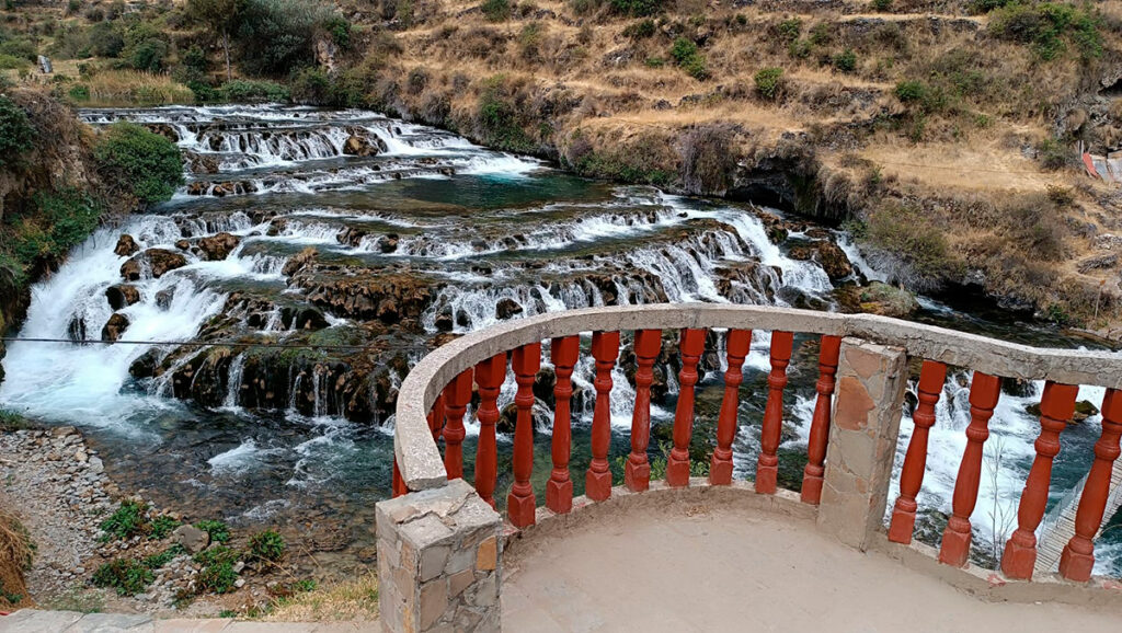 Mirador de Huancaya frente a una serie de caídas escalonadas, con baranda circular y quebrada altoandina en segundo plano