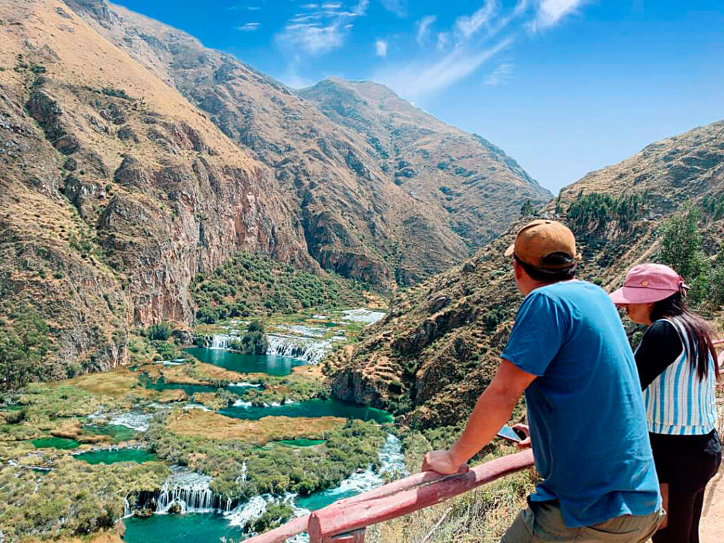 Visitantes observan la laguna Huallhua y sus caídas escalonadas desde un mirador elevado en el valle de Huancaya
