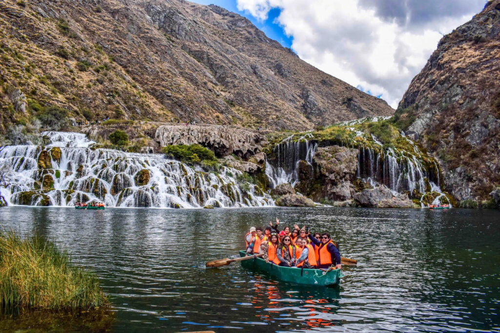 Río y cascadas en Huancaya, Yauyos, con visitantes en bote frente a un paisaje andino marcado por el agua y el relieve de la sierra central