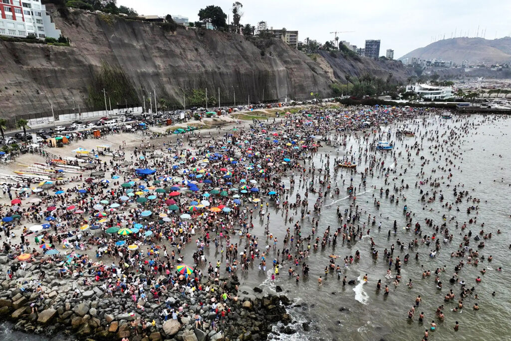 Playa Agua Dulce en temporada alta, con gran afluencia de bañistas y vista del acantilado de Chorrillos