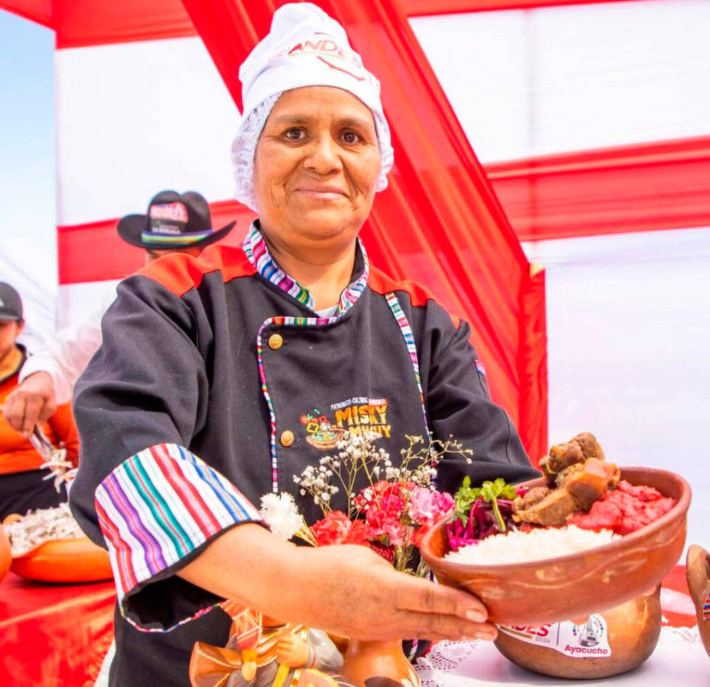 Cocinera ayacuchana sostiene un plato tradicional de Puca Picante servido en olla de barro durante una feria gastronómica regional