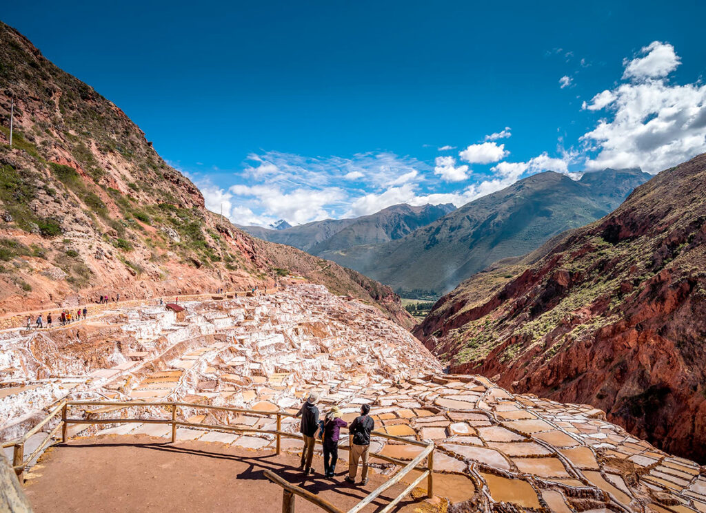 Vista panorámica de las Salineras de Maras con visitantes observando las pozas de sal escalonadas sobre la ladera del Valle Sagrado del Cusco