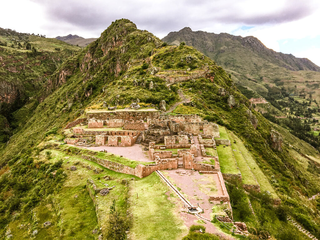 Vista panorámica de las construcciones incas de Pisac asentadas sobre la ladera del valle, con terrazas agrícolas y montañas alrededor