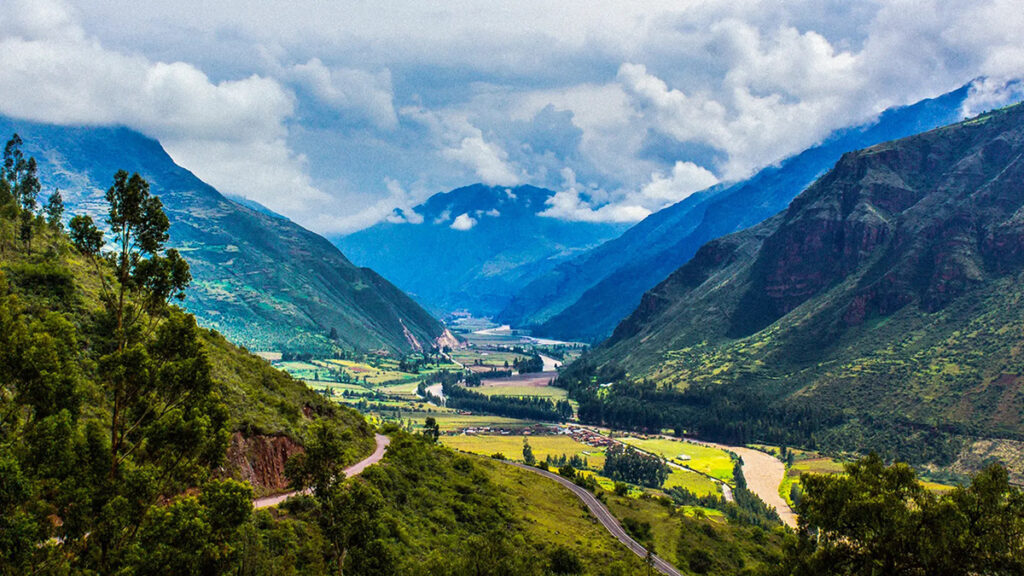 Vista amplia del Valle Sagrado de los Incas con el río Urubamba, áreas agrícolas y laderas verdes distribuidas en terrazas.