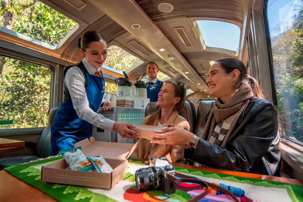 Tripulantes del PeruRail Vistadome Observatory atendiendo a pasajeros durante el viaje hacia Machu Picchu, con servicio a bordo y atención personalizada