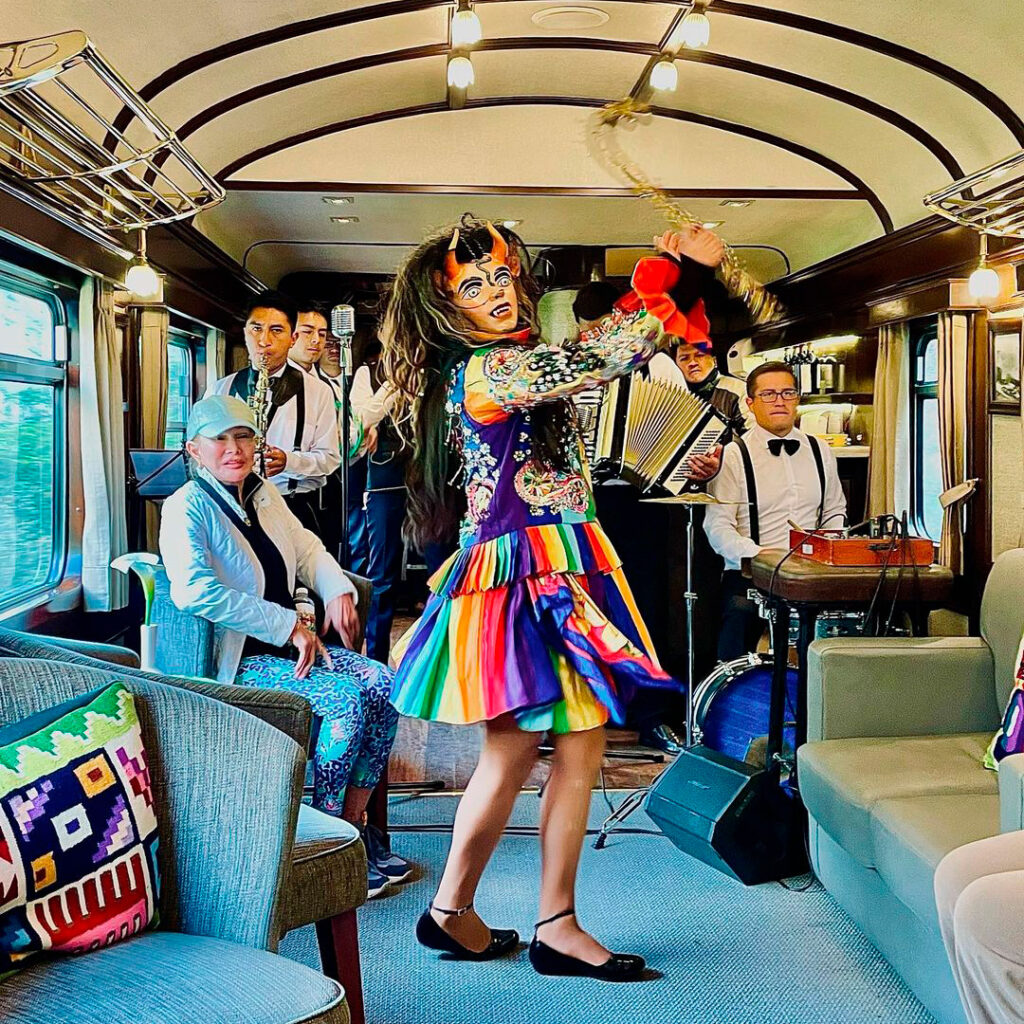 Artistas interpretando música andina en vivo dentro del coche bar del PeruRail Vistadome Observatory rumbo a Machu Picchu