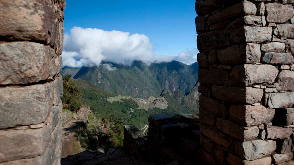 Vista desde la Puerta del Sol hacia Machu Picchu, enmarcada por muros incas de piedra