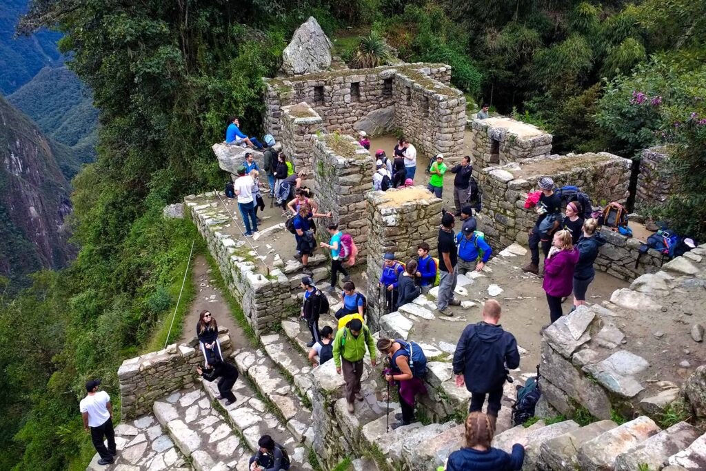 Grupo de visitantes en una terraza inca del sendero a Intipunku, con vistas al valle de Machu Picchu