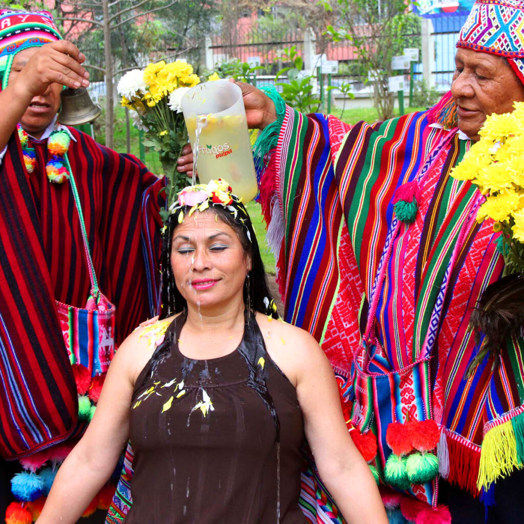 Mujer haciendo el baño de floreciminto. Dos chamanes andinos haciendo baño de florecimiento a turista.